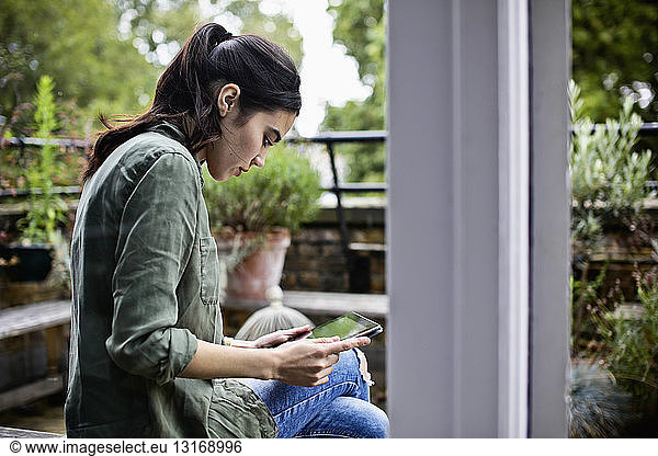 Woman using digital tablet by terrace