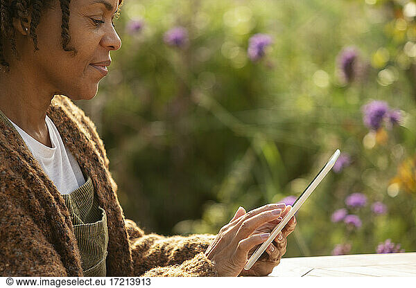 Woman using digital tablet in sunny garden