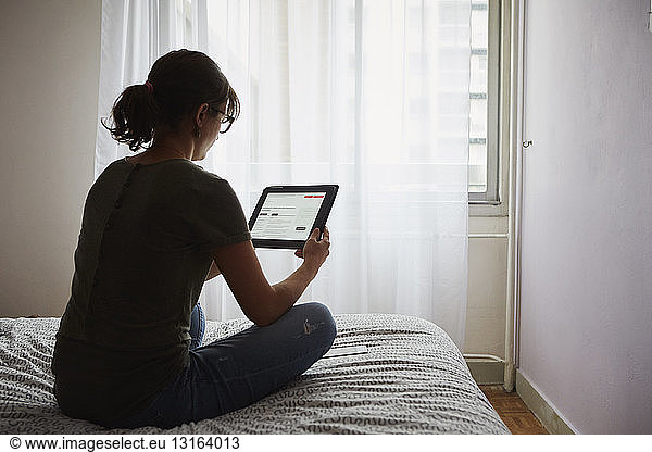 Woman using digital tablet on bed