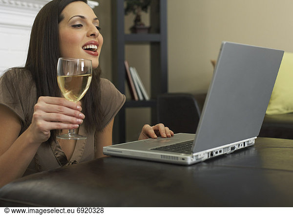 Woman Using Laptop and Drinking Wine