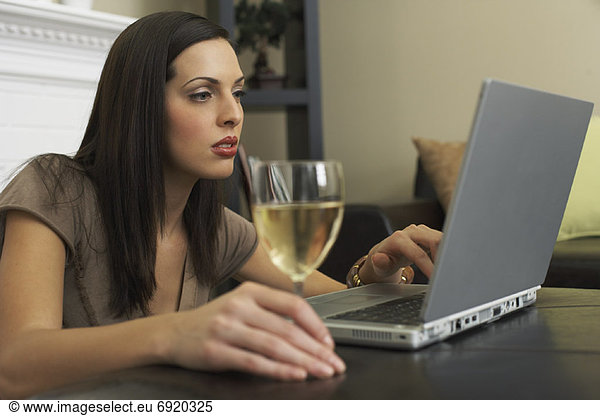 Woman Using Laptop Computer  Drinking Glass of Wine