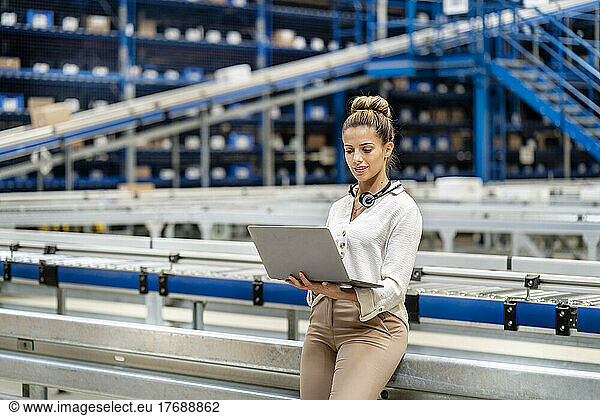 Woman using laptop in warehouse