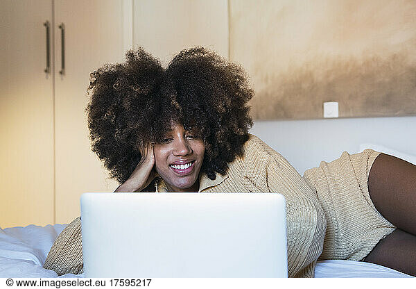 Woman using laptop lying on bed at home