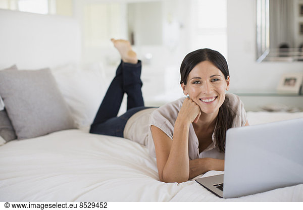 Woman using laptop on bed