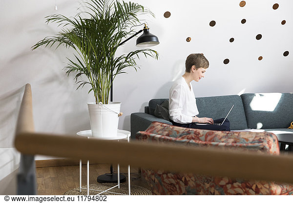 Woman using laptop on couch in modern office