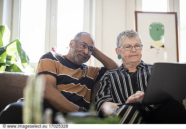 Woman using laptop while man sitting by on sofa