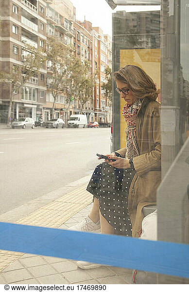 Woman using mobile phone at bus stop