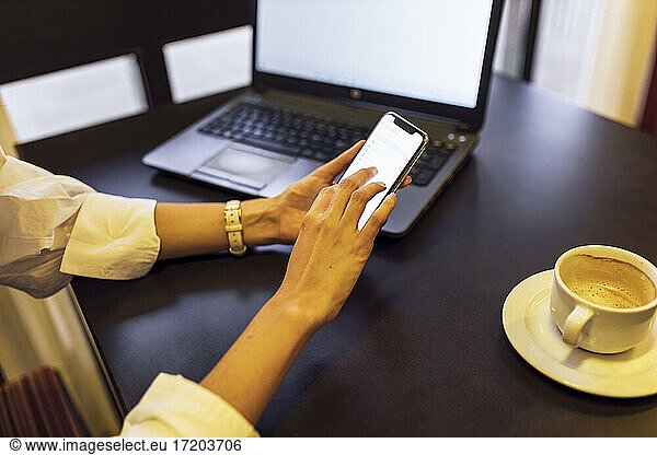 Woman using mobile phone sitting at cafe