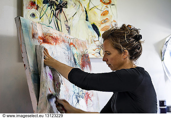 Woman using paint roller and fabric while painting