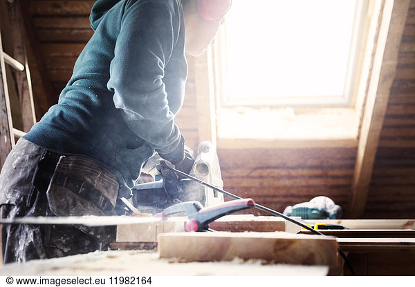Woman using power tool while renovating old attic