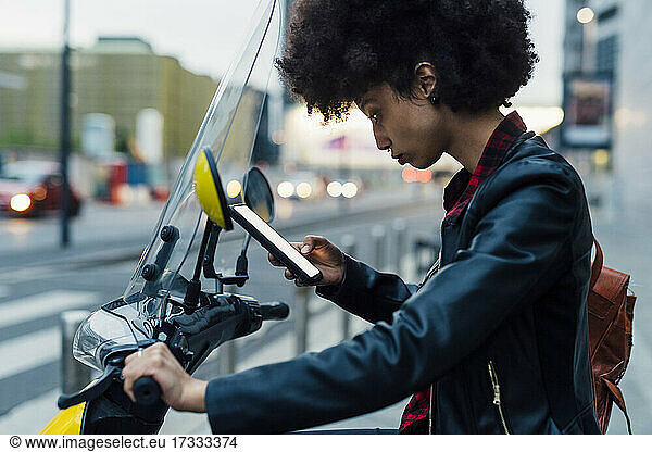 Woman using rental motor scooter through smart phone