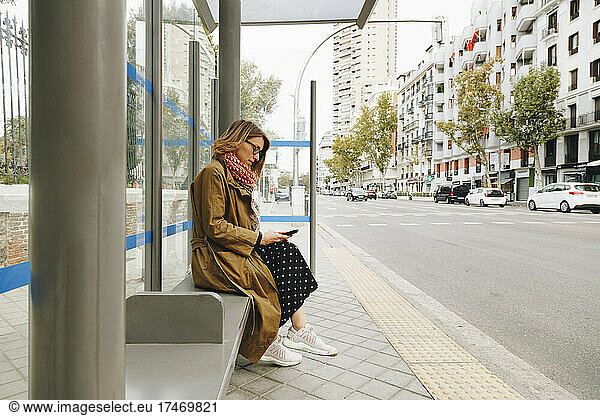 Woman using smart phone at bus stop