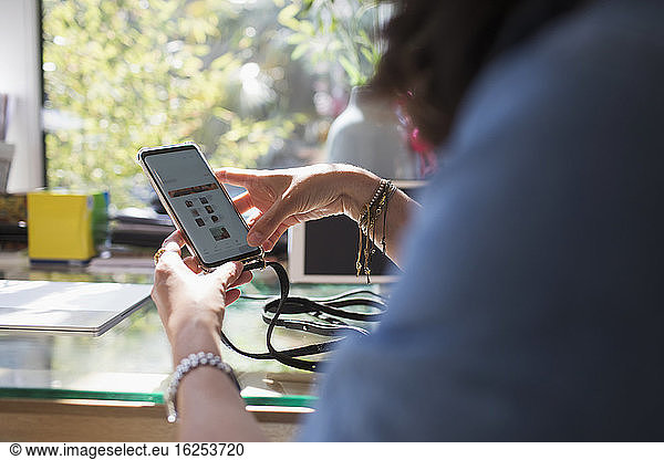 Woman using smart phone at desk in home office