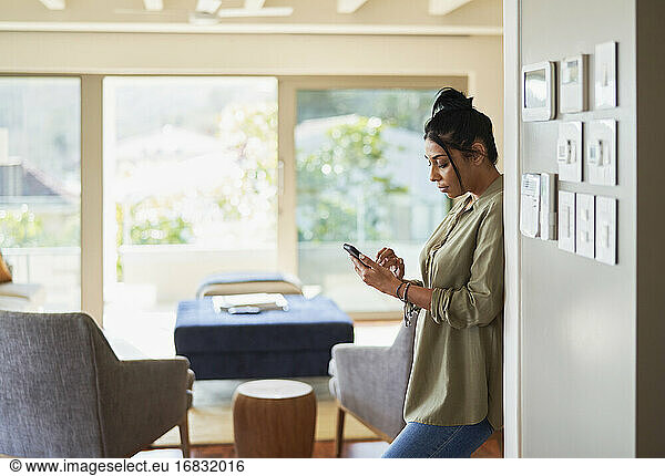 Woman using smart phone by home automation controls