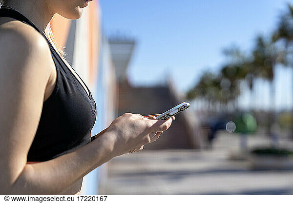 Woman using smart phone during sunny day