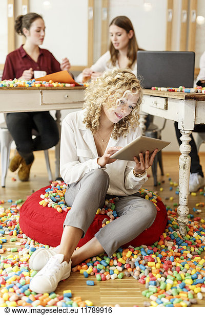 Woman using tablet in office surrounded by colorful polystyrene parts