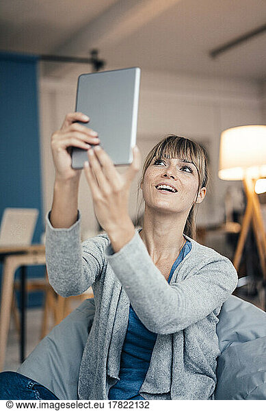 Woman video calling through tablet PC at home