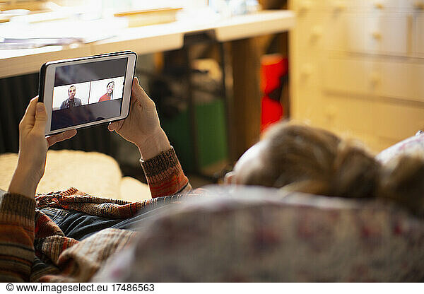 Woman video chatting with colleagues on digital tablet screen