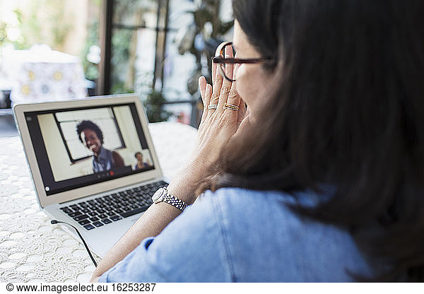 Woman video conferencing with colleagues at laptop screen