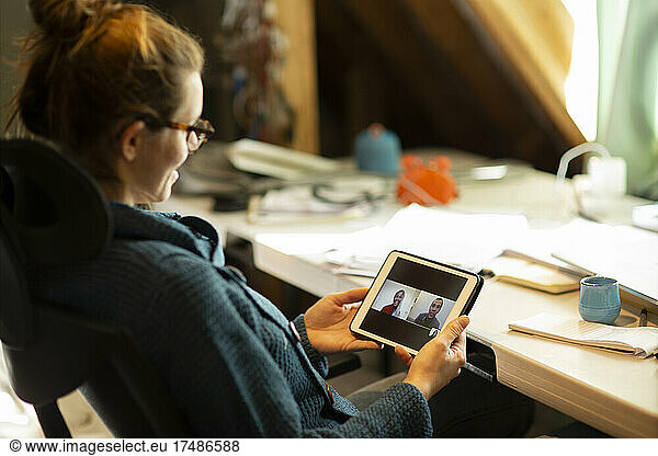 Woman video conferencing with colleagues on digital tablet screen