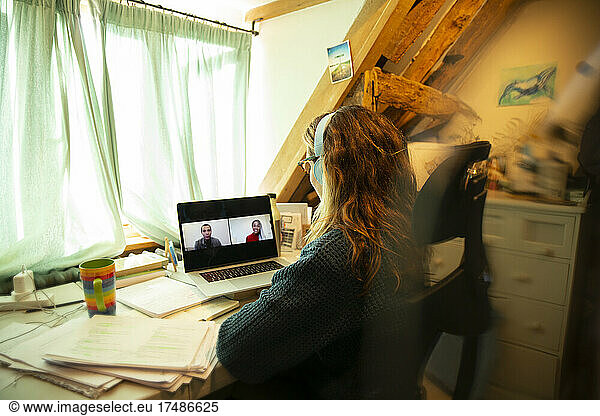 Woman video conferencing with colleagues on laptop screen at home