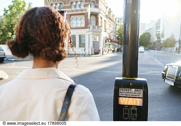 Woman waiting by pedestrian crossing button