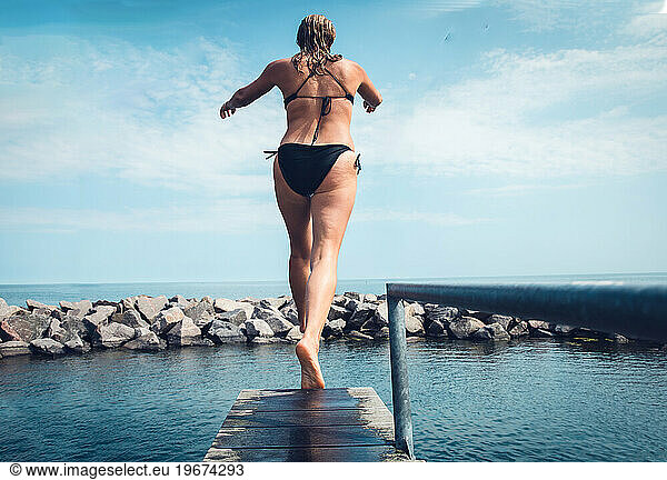 Woman Walking A Diving Board Into The Ocean In Scandinavia