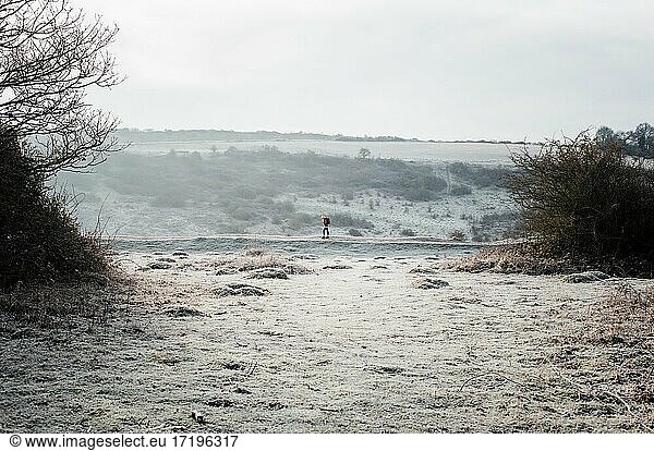 woman walking along a frosty path in the English countryside in winter