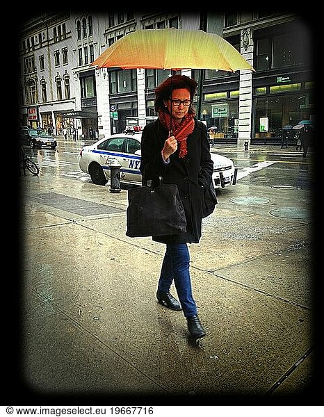 Woman walking in the rain with umbrella NYC NY USA