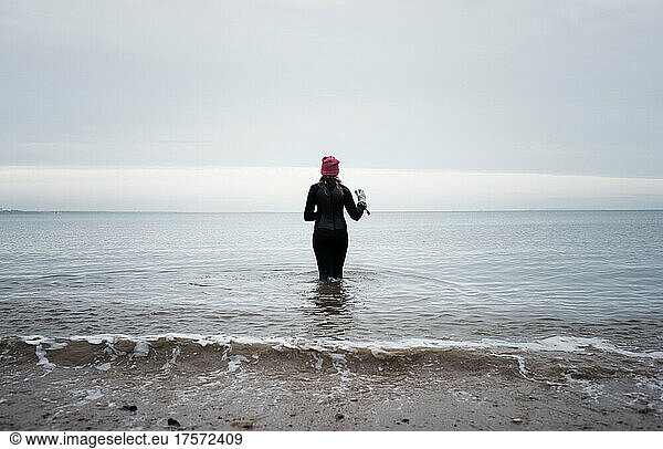 woman walking into the ocean ready for cold water swimming
