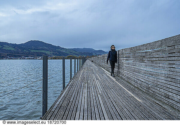 woman walking on boardwalk over lake close to Zurich