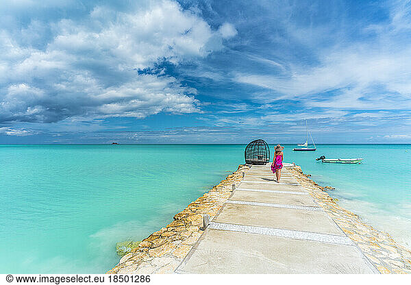 Woman walking on jetty towards a luxury gazebo over Caribbean Sea