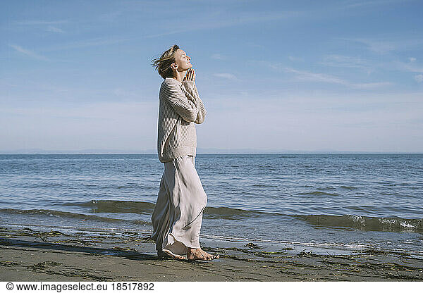 Woman walking on shore at beach in front of sky