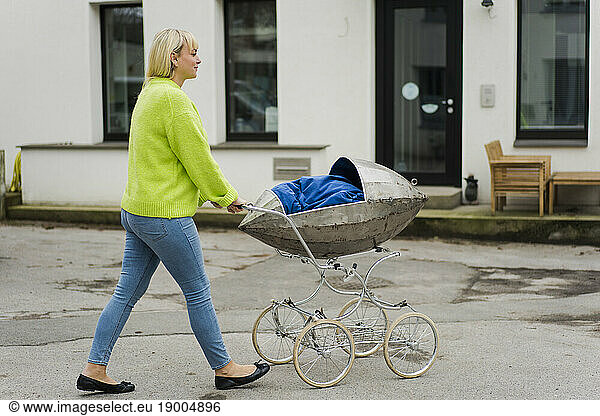 Woman walking with baby stroller on road