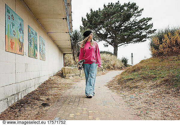 woman walking with her skateboard at an urban park at the beach