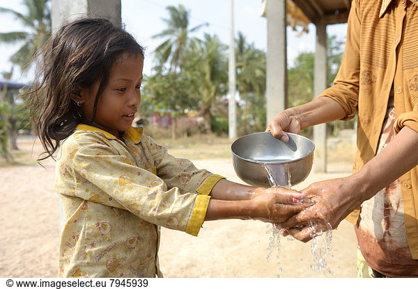 Woman washing a girl's hands  hygiene education