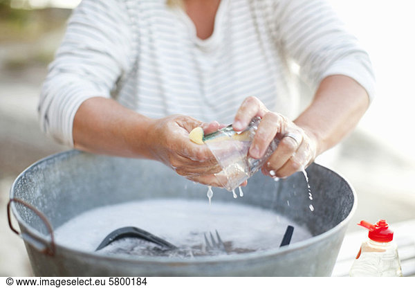 Woman washing glass in soap water filled container
