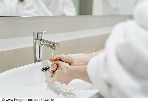 Woman washing hands in hotel bathroom