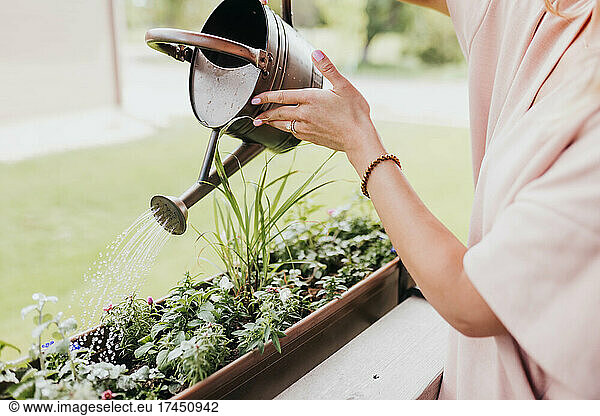 Woman waters plants outside of home in midwest