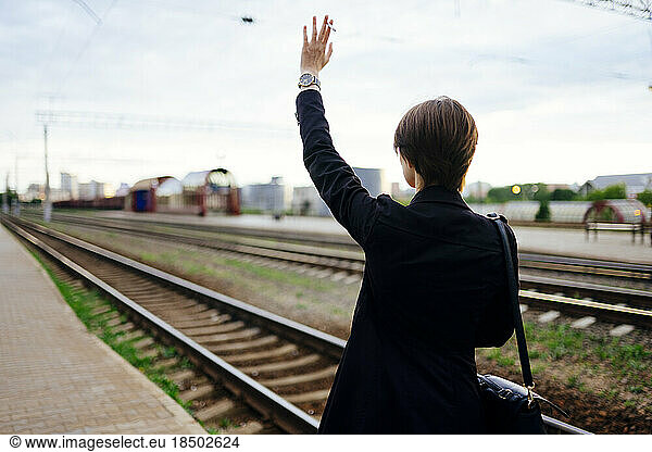 Woman waving hand leaving train