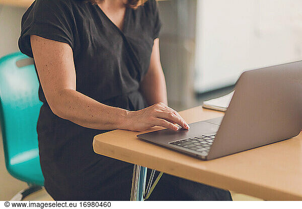 Woman wearing a black dress working on her laptop.