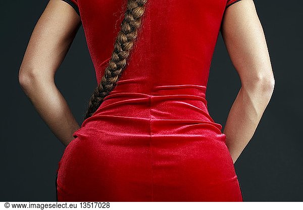 Woman wearing a red velvet dress and pony tail from behind  partial view