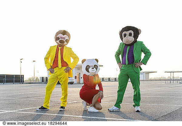 Woman wearing animal mask crouching with friends standing in parking lot