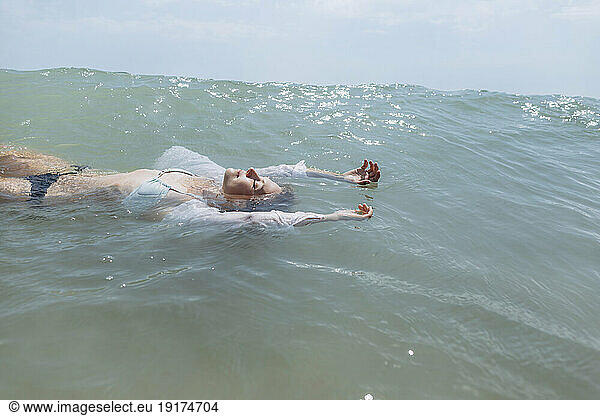 Woman wearing bikini floating on water in sea