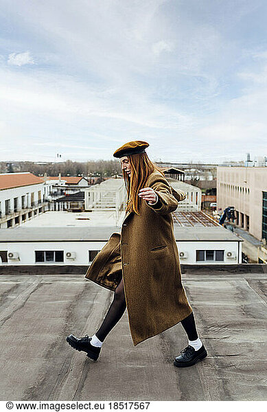 Woman wearing coat walking on building terrace