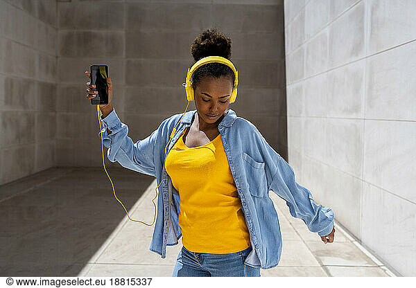 Woman wearing denim shirt listening to music at sunny day