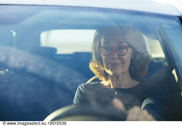Woman wearing eyeglasses driving car seen through windshield