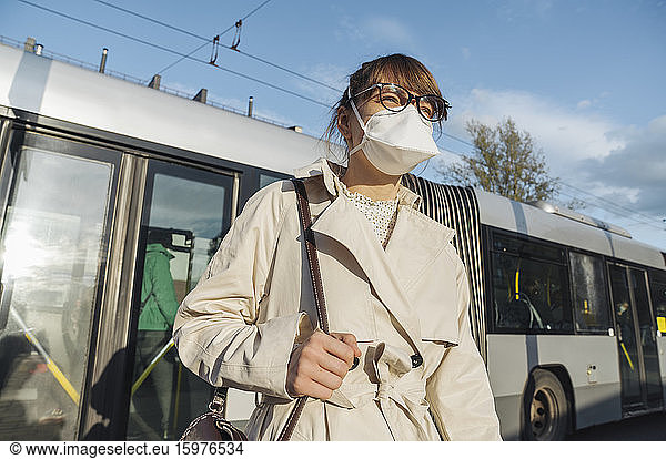 Woman wearing face mask getting off the bus in the city