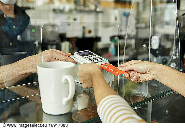 Woman wearing face mask holding contactless payment device  customer paying by mobile phone