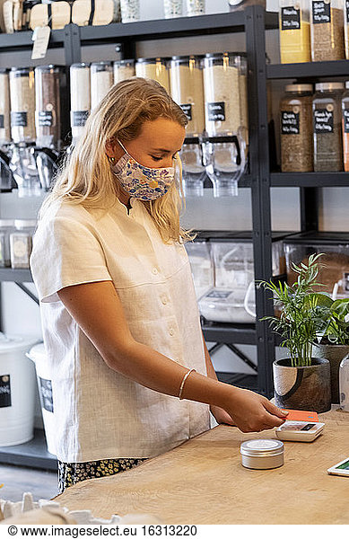 Woman wearing face mask shopping in a local store  making contactless payment